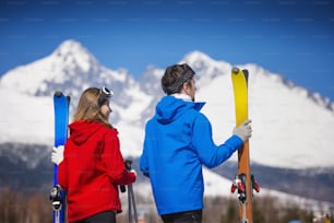 Casal jovem esquiando ao ar livre em montanhas ensolaradas de inverno