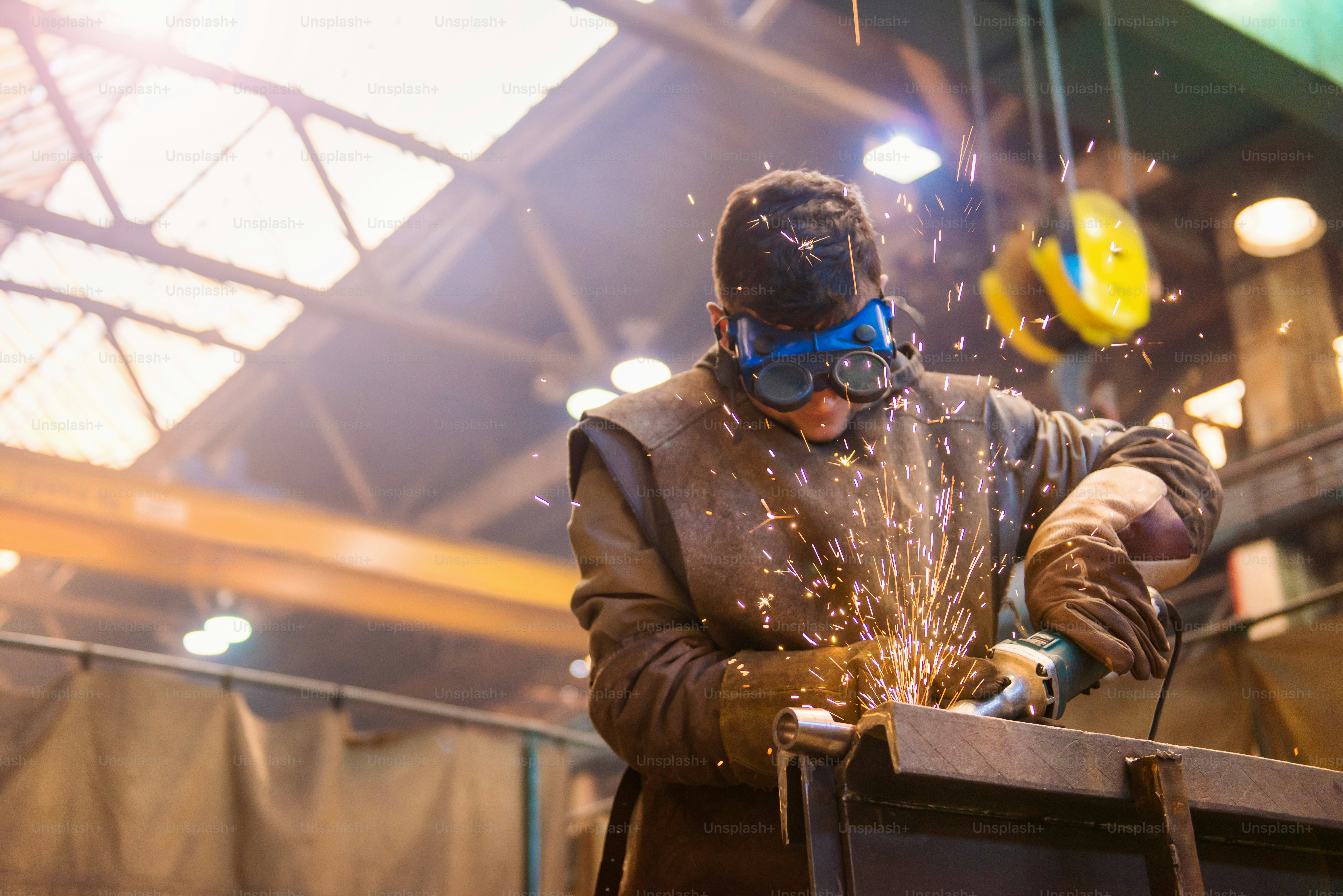 Young man with protective goggles welding in a factory