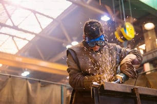 Young man with protective goggles welding in a factory