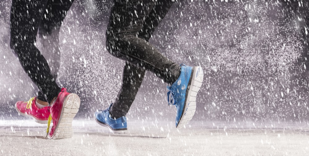 Athlete woman is running during winter training outside in cold snow weather.