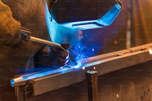 Young man with protective mask welding in a factory