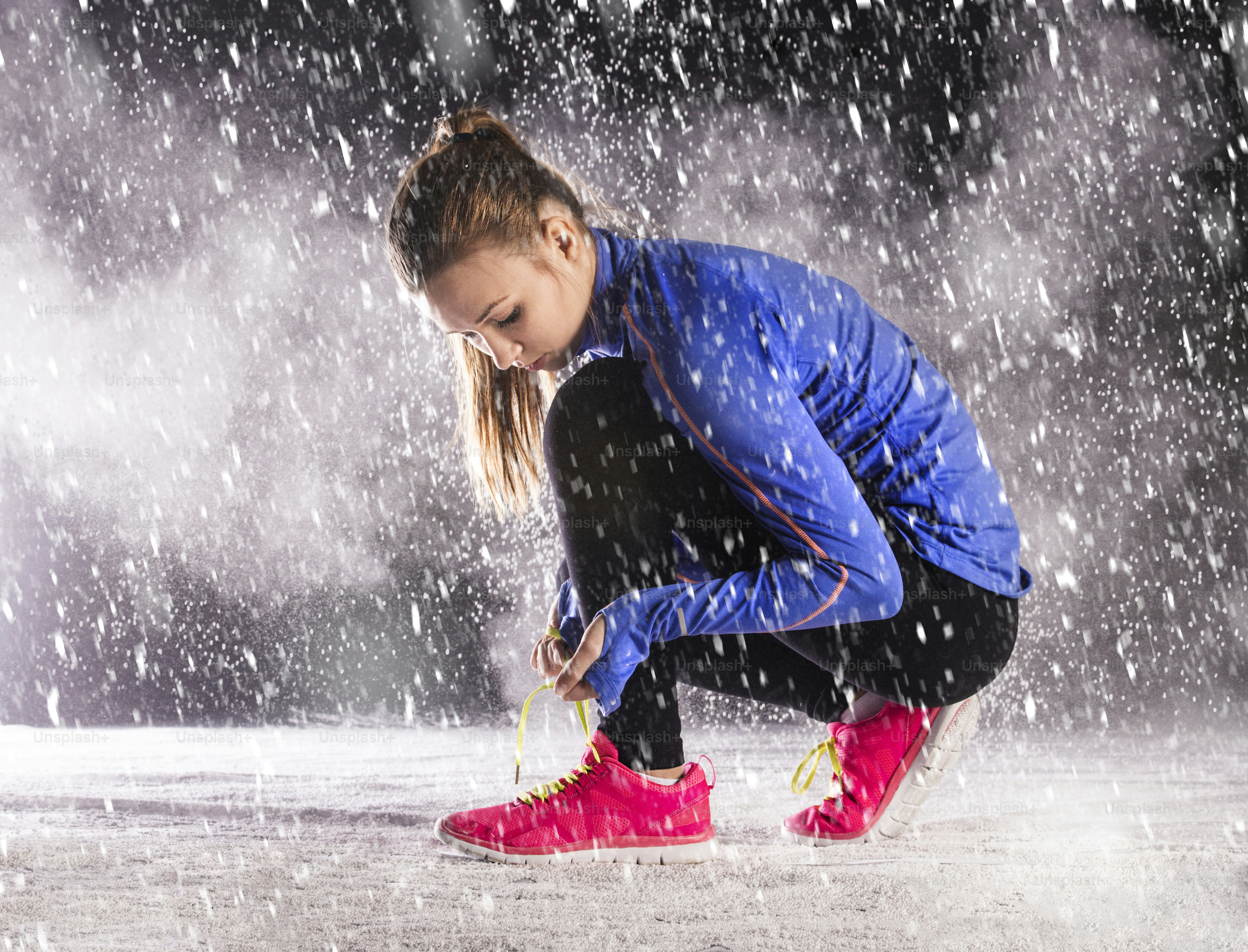 Athlete woman is running during winter training outside in cold snow ...