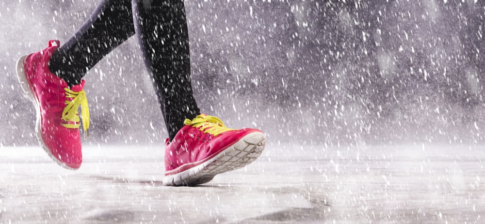 La mujer atleta está corriendo durante el entrenamiento de invierno al aire libre en un clima frío de nieve.