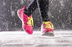 Athlete woman is running during winter training outside in cold snow weather.