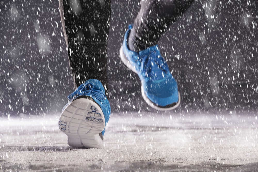 La donna atleta sta correndo durante l'allenamento invernale all'aperto nel freddo tempo della neve.