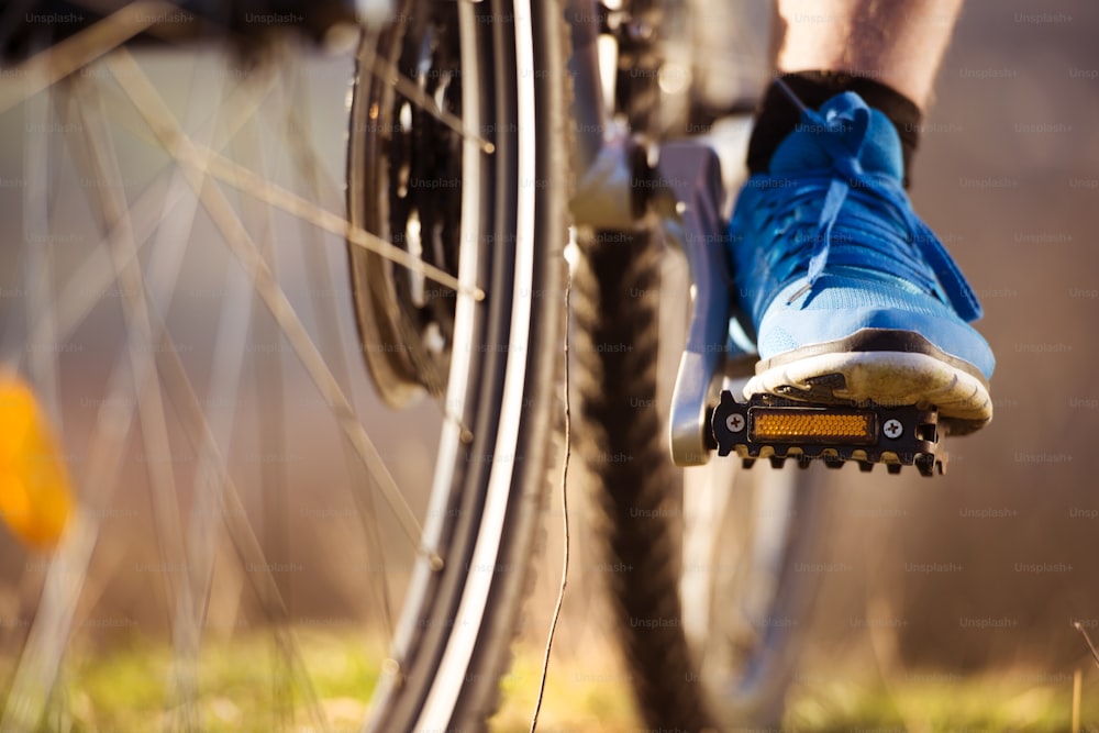 Primer plano de las piernas del hombre del ciclista montando en bicicleta de montaña en el sendero al aire libre en la naturaleza