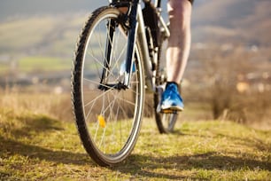 Closeup of cyclist man legs riding mountain bike on outdoor trail in nature