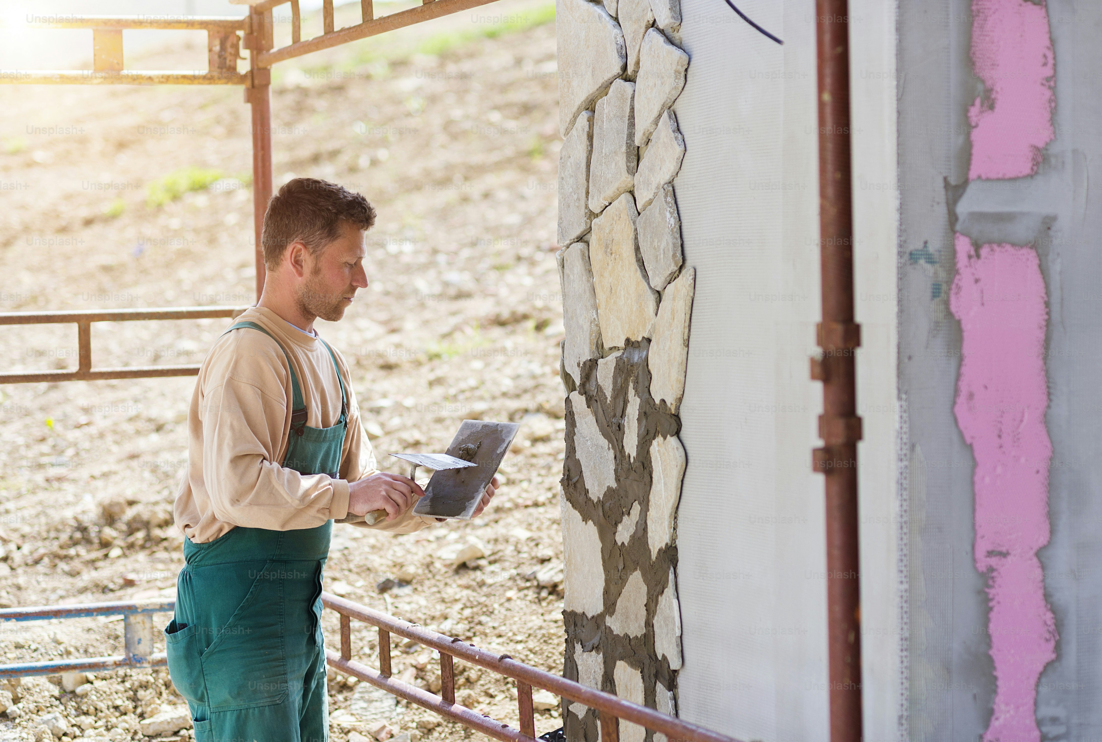 Muratore che mette pietre naturali decorative su una parete