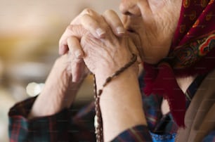 Detalle de una mujer muy anciana con pañuelo en la cabeza rezando