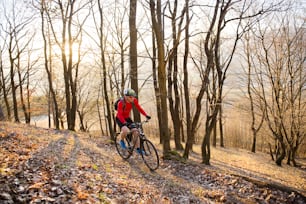 秋の森の屋外トレイルでマウンテンバイクに乗るサイクリストの男