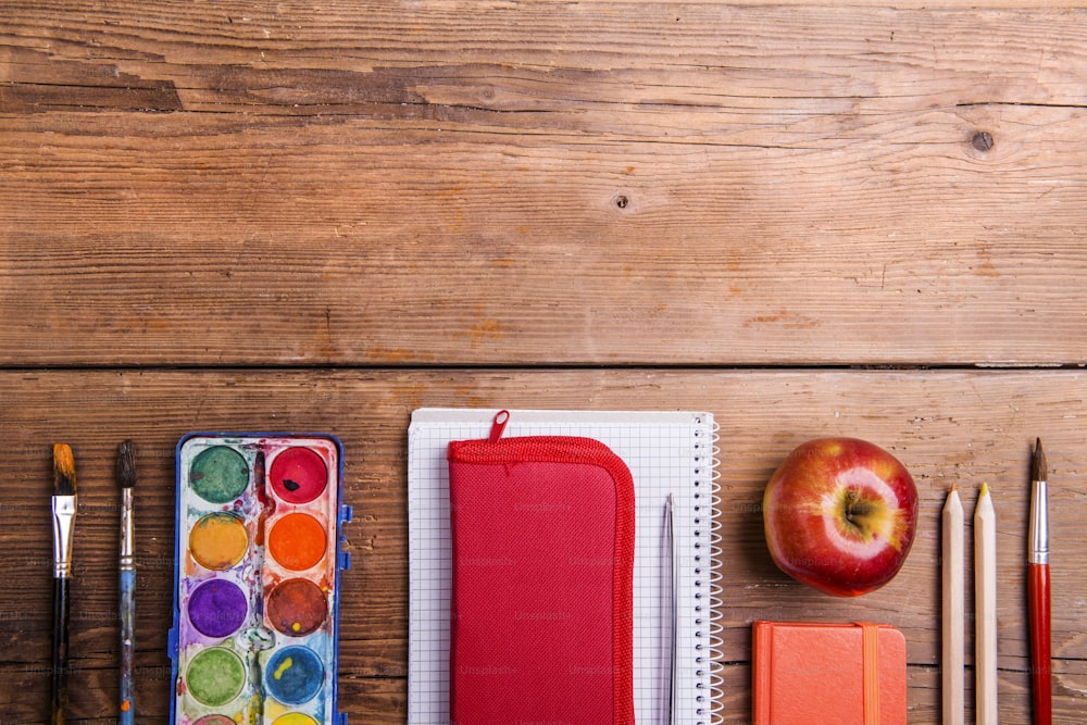 Desk with school supplies. Studio shot on wooden background.