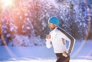 Young sportsman jogging outside in sunny winter park