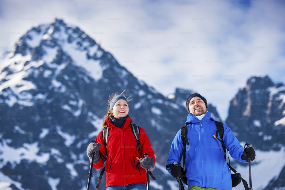 Young couple hiking outside in sunny winter mountains