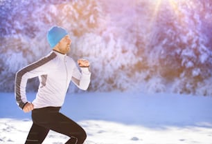 Giovane sportivo che fa jogging fuori nel soleggiato parco invernale