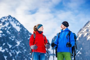 Jeune couple en randonnée à l’extérieur dans les montagnes ensoleillées d’hiver