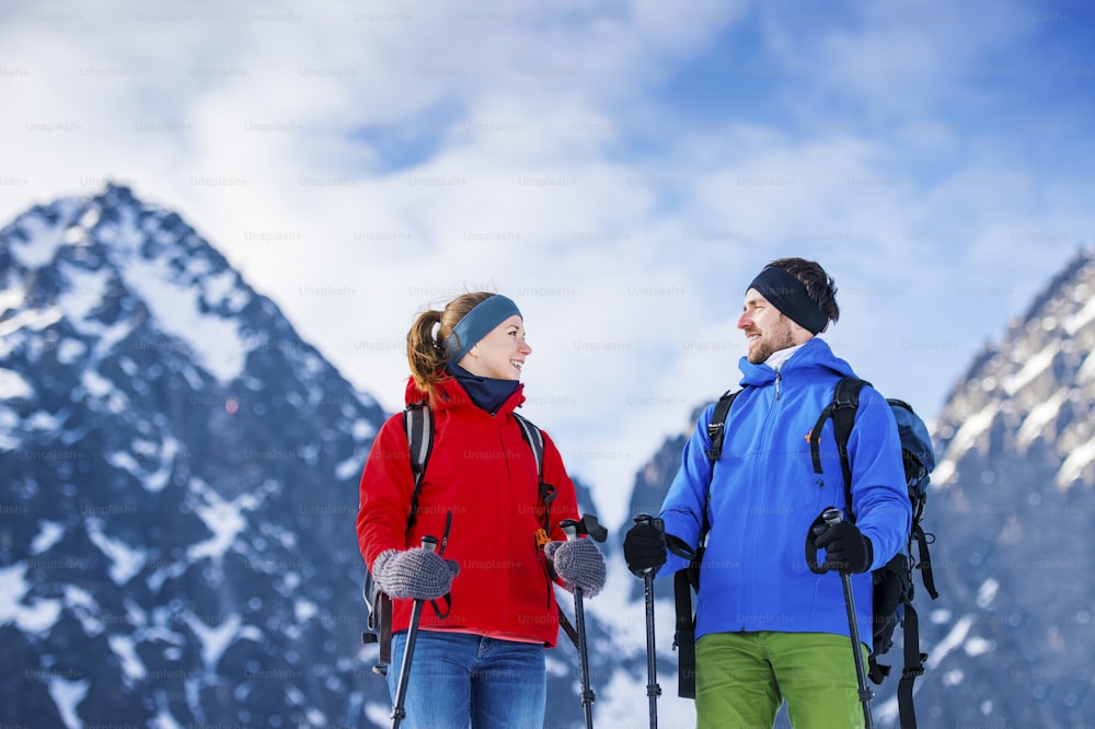 Pareja joven que camina al aire libre en las soleadas montañas de invierno