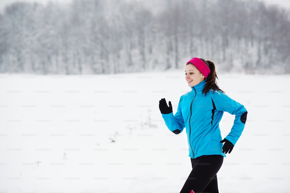 Sportlerin läuft während des Wintertrainings draußen bei kaltem Schneewetter.