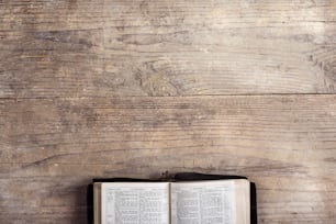 Bíblia aberta em um fundo de mesa de madeira.