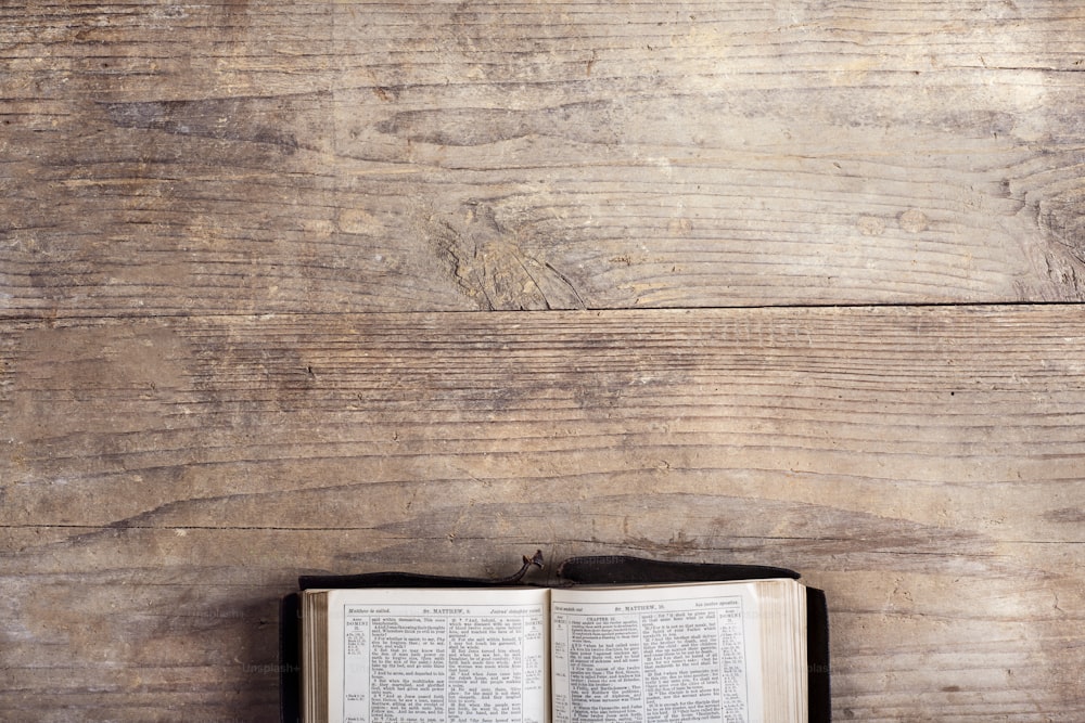Bibbia aperta su uno sfondo di scrivania in legno.