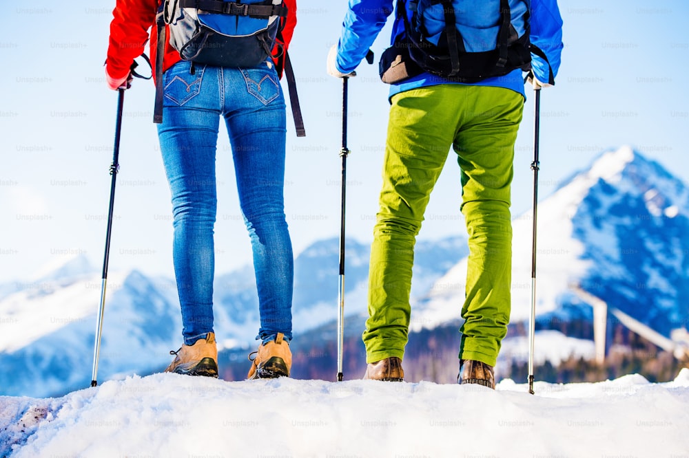 Young couple hiking outside in sunny winter mountains