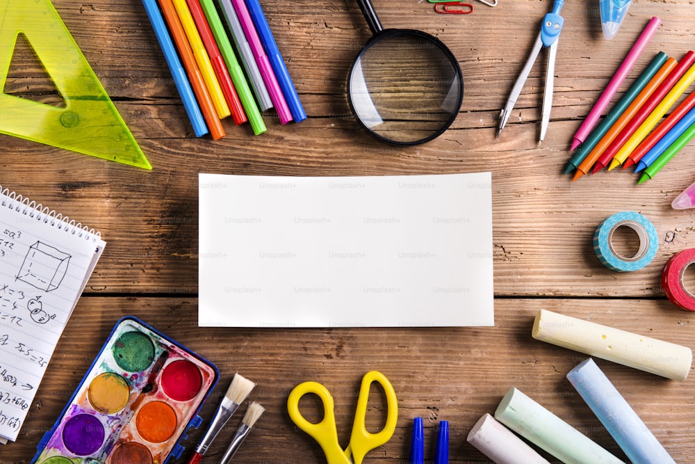 Desk with school supplies. Studio shot on wooden background.