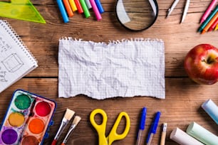 Desk with school supplies. Studio shot on wooden background.