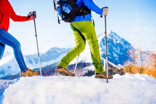 Junges Paar, das draußen in sonnigen Winterbergen wandert