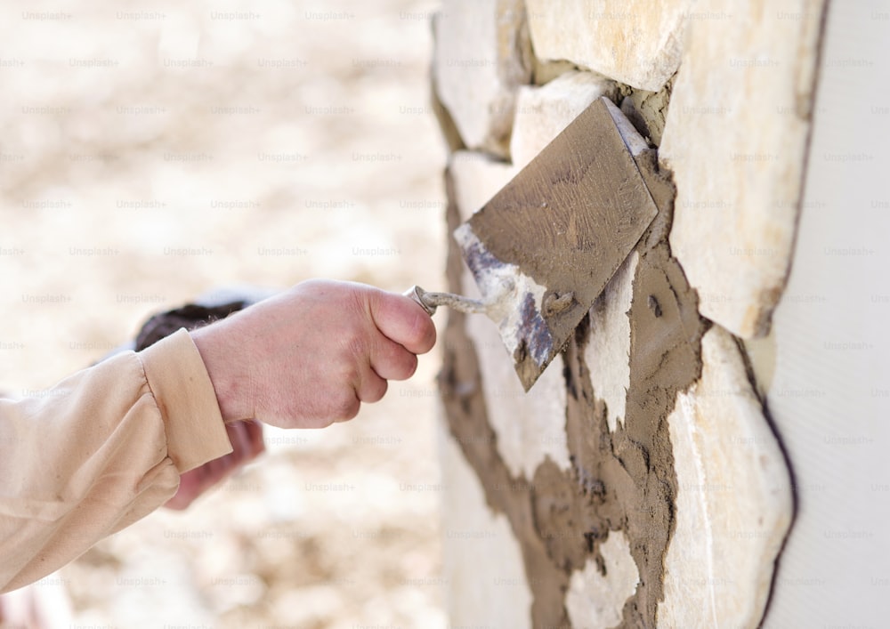 Mason putting decorative natural stones on a wall