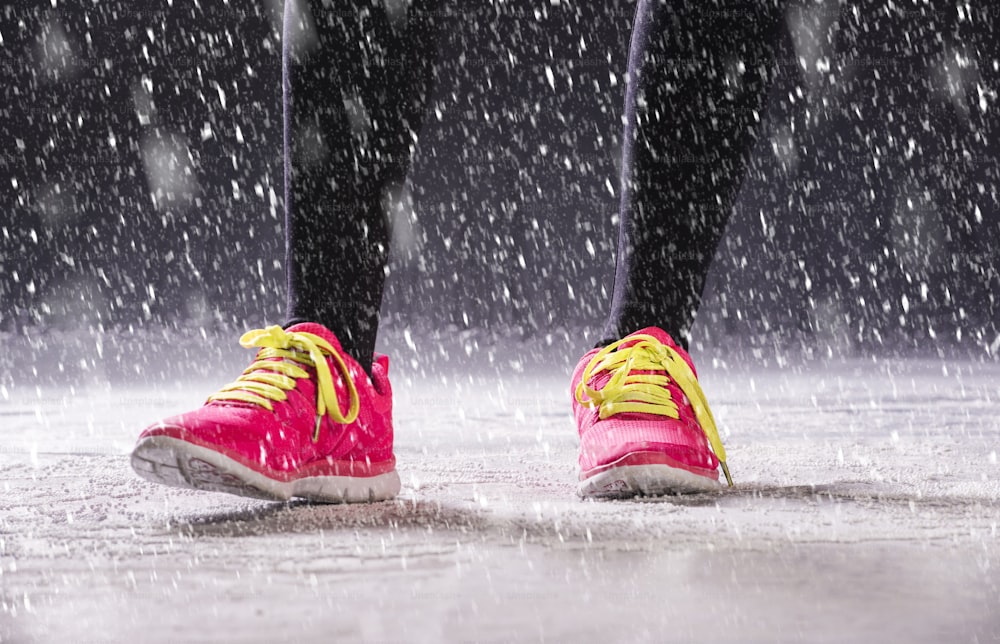 Athlete woman is running during winter training outside in cold snow weather.