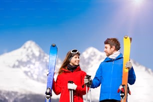 Casal jovem esquiando ao ar livre em montanhas ensolaradas de inverno