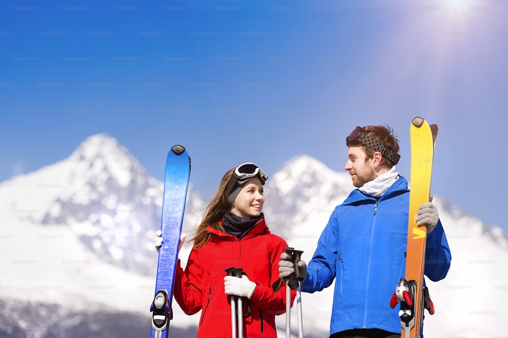 Junges Paar beim Skifahren draußen in sonnigen Winterbergen