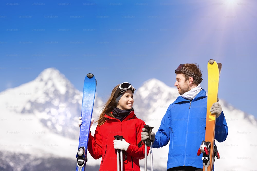 Young couple skiing outside in sunny winter mountains