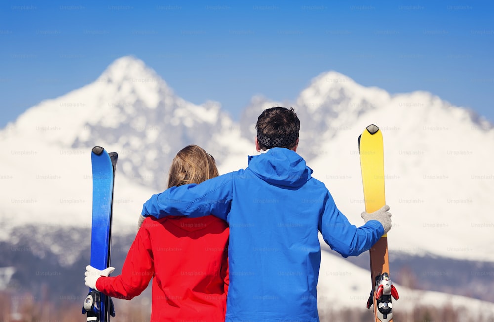 Junges Paar beim Skifahren draußen in sonnigen Winterbergen