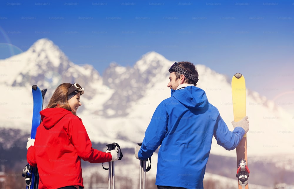 햇볕이 잘 드는 �겨울 산에서 스키를 타는 젊은 부부