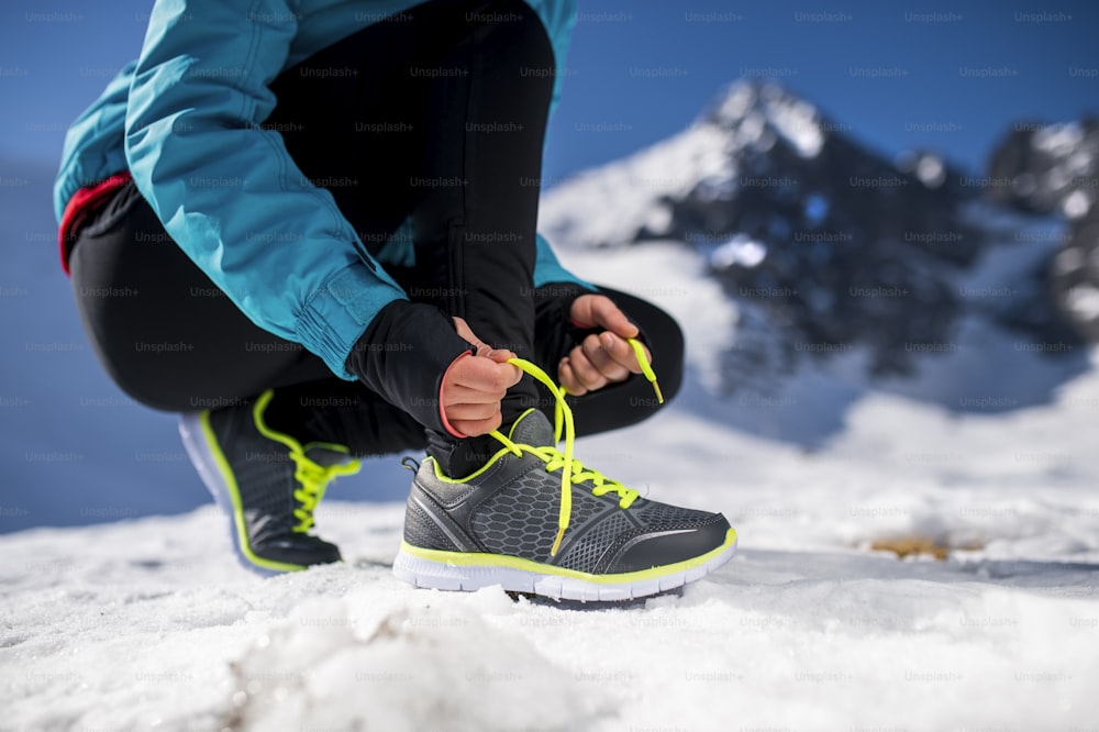 Young runner tying her shoelaces outside in winter nature