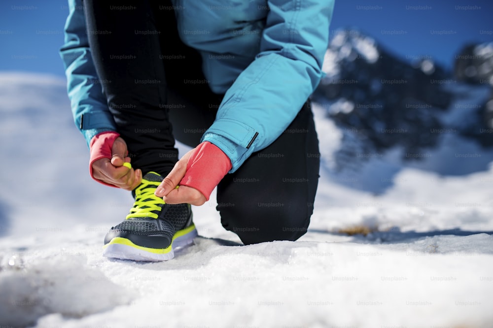 Young runner tying her shoelaces outside in winter nature