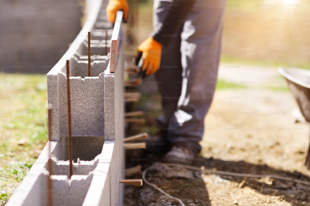 Bricklayer putting down another row of bricks in site