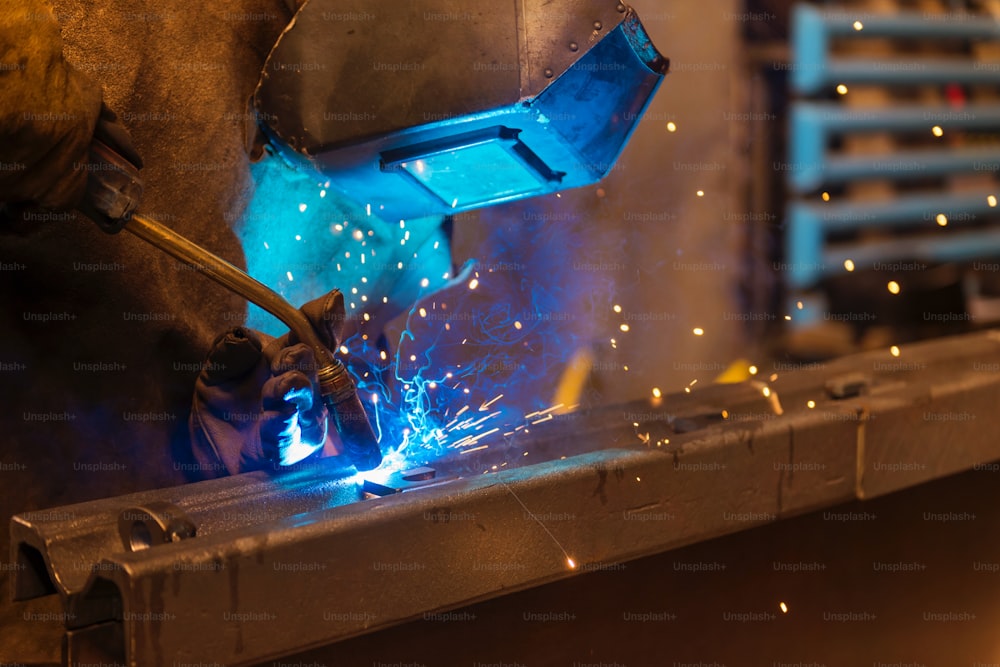 Young man with protective mask welding in a factory