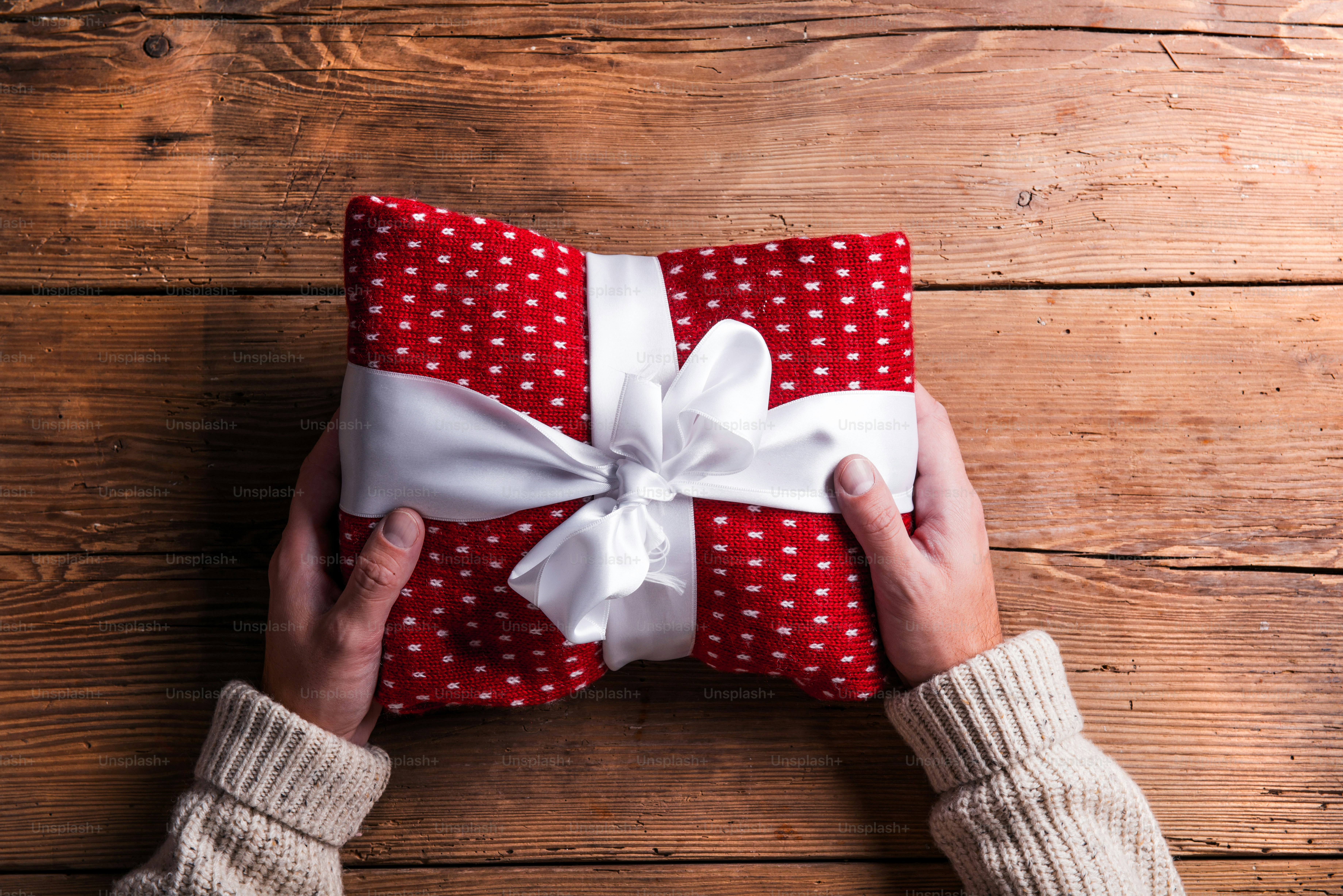 Man holding Christmas present laid on a wooden table background