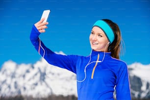 Jeune femme faisant du jogging à l’extérieur dans les montagnes ensoleillées d’hiver