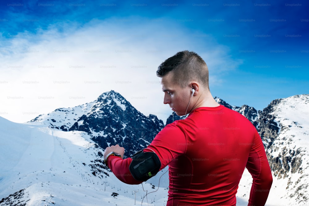 Jeune homme faisant du jogging à l’extérieur dans les montagnes ensoleillées d’hiver