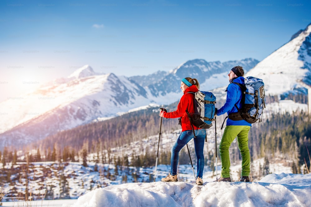 Young couple hiking outside in sunny winter mountains