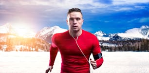 Jeune homme faisant du jogging à l’extérieur dans les montagnes ensoleillées d’hiver