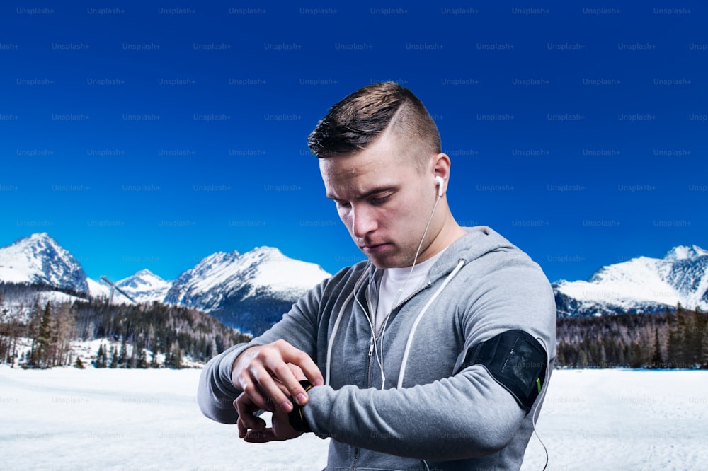 Young man jogging outside in sunny winter mountains