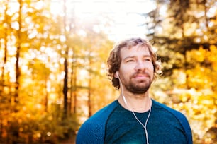 Joven corredor guapo al aire libre en la naturaleza soleada del otoño