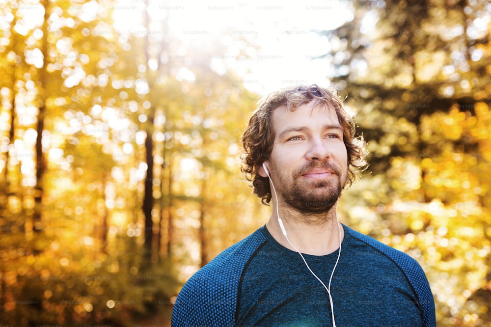 Young handsome runner outside in sunny autumn nature