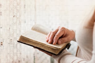 Unrecognizable woman holding a bible in her hands and praying