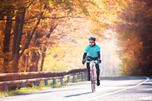 Young handsome sportsman riding his bicycle outside in sunny autumn nature