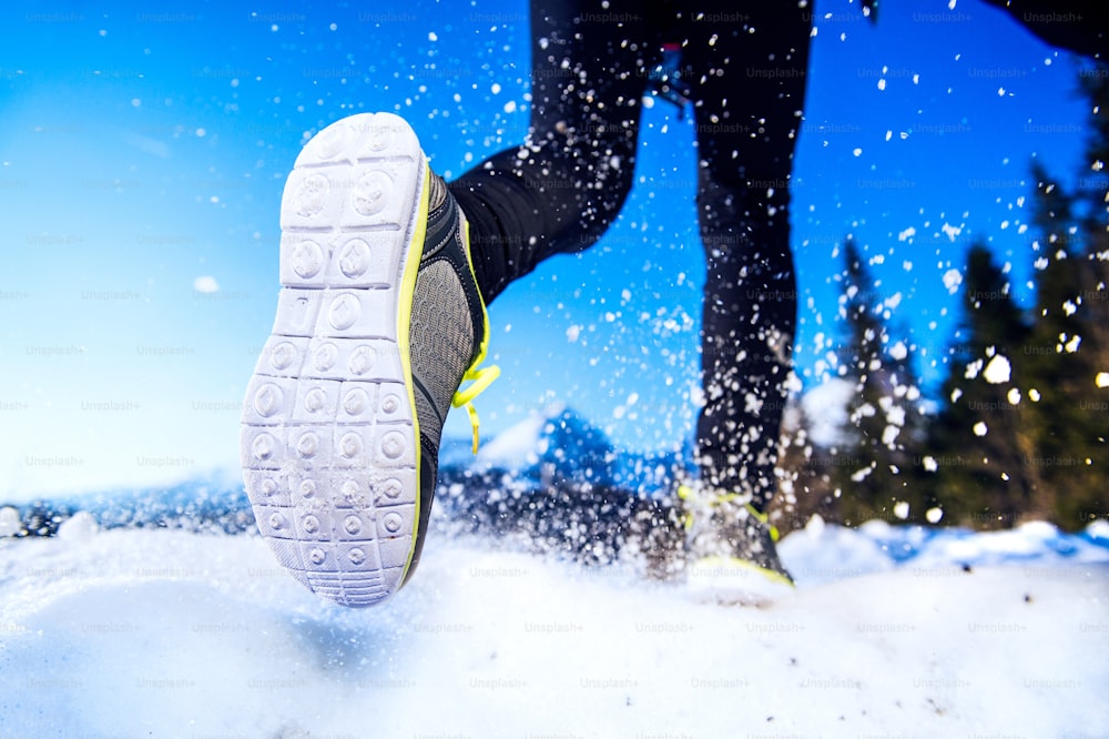 Piernas de un joven corredor al aire libre en la naturaleza invernal