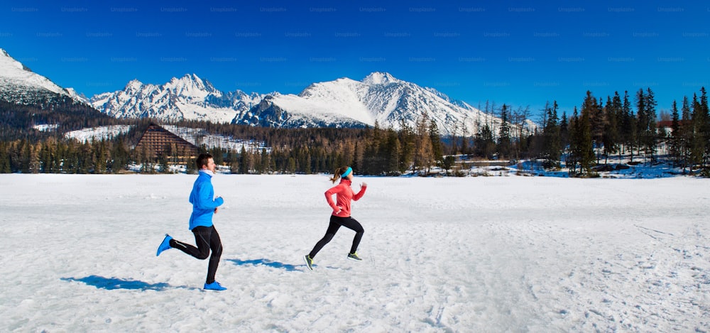 Young couple jogging outside in sunny winter mountains